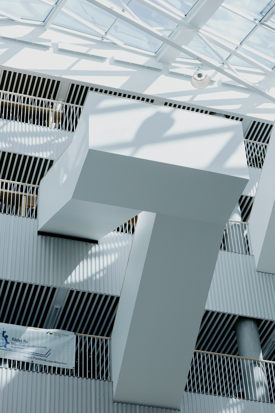 Interno di un moderno edificio bianco con ombre geometriche e soffitto in vetro.